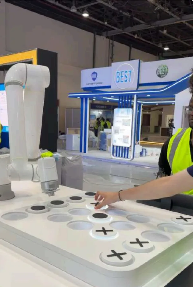 A visitor placing an X puck on the board while the robot waits